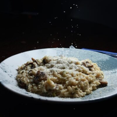 Creamy mushroom risotto with parmesan cheese being sprinkled on top