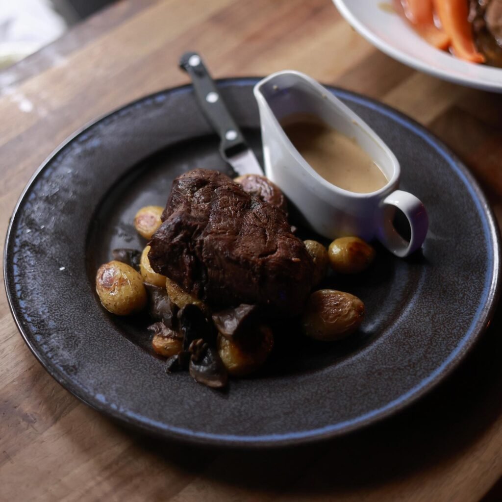 Grilled fillet steak with baby roast potatoes, garlic mushrooms and peppercorn sauce