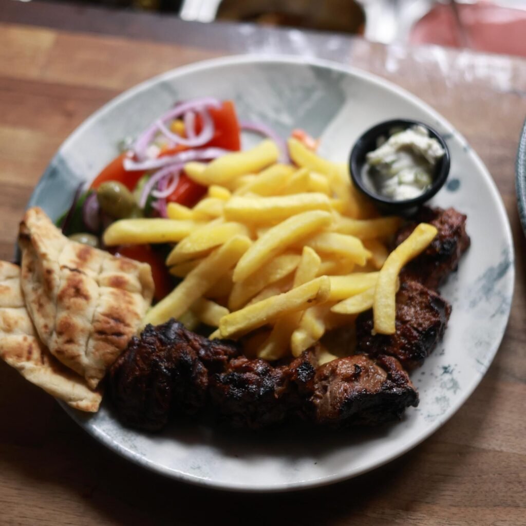 Grilled lamb skewer served with chips, pitta bread, Greek salad and tzatziki